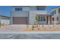 Two-story home with a modern exterior, stone accents, a brick driveway, and a two-car garage at 9265 Frazer St, Las Vegas, NV 89166