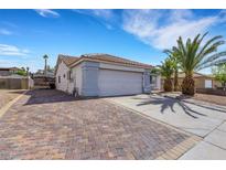 Charming single-story home with a spacious driveway, two-car garage, and desert landscaping with mature palm trees at 341 Waterwheel Falls Dr, Henderson, NV 89015