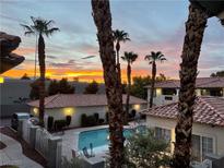 Charming community pool surrounded by lush landscaping and red tile roofs, under a beautiful sunset sky at 3420 Winterhaven St # 202, Las Vegas, NV 89108