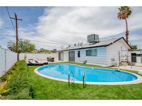 Backyard features a sparkling blue pool surrounded by lush green turf and complimented by lounge chairs at 6301 Garwood Ave, Las Vegas, NV 89107