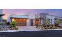 Modern home showcasing stone accents, a two-car garage, and well-manicured landscaping at sunset at 10482 Calico Terrace Ave, Las Vegas, NV 89135