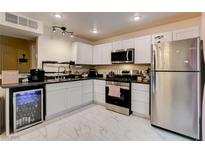 Well-equipped kitchen with sleek white cabinetry, stainless steel appliances, and a built-in beverage cooler at 3322 Dragon Fly St, North Las Vegas, NV 89032