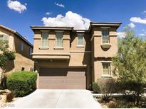 Two story home with tan stucco, a two-car garage and a concrete driveway under a partly cloudy sky at 8550 Bright Bush St, Las Vegas, NV 89131