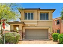 Two-story tan home featuring a two-car garage and stone accents under a blue sky at 10805 Cain Ave, Las Vegas, NV 89166