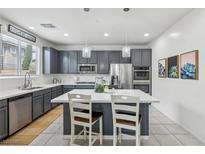 Modern kitchen with stainless steel appliances, gray cabinets, and a center island with white countertop at 160 Lilt Ave, Henderson, NV 89011