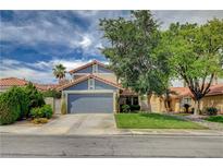 Charming two-story home with a well-manicured lawn, mature trees, and a gray two car garage at 2412 Muirfield Ave, Henderson, NV 89074