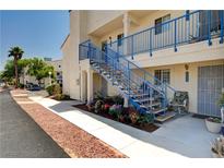 Charming condo exterior featuring blue railings, landscaped flower beds, and a welcoming walkway at 2725 S Nellis Blvd # 1038, Las Vegas, NV 89121