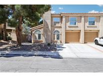 Charming townhome featuring a two-car garage and desert landscaping with mature trees at 2830 Crystal Lantern Dr, Henderson, NV 89074