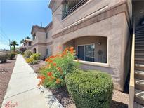 Beige two-story condo building with desert landscaping, walkway, and stair access at 5750 E Hacienda Ave # 107, Las Vegas, NV 89122
