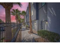 View of the exterior with multiple Palm Trees aligned along the walkway and a secure fence at 9050 W Tropicana Ave # 1015, Las Vegas, NV 89147