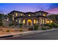 Stunning two-story home with a stone facade, arched entryway, and meticulously manicured landscaping at 12021 La Palmera Ave, Las Vegas, NV 89138