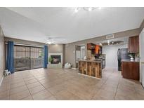 Open living room with fireplace, tile flooring, and sliding glass doors to the outside patio at 2995 E Sunset Rd # 134, Las Vegas, NV 89120