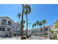 Gated community entrance featuring palm trees and well-maintained buildings under a bright blue sky at 3125 N Buffalo Dr # 2104, Las Vegas, NV 89128