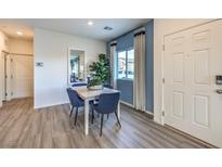 Bright dining area features wood-look floors, a white table with navy chairs, and natural light at 7935 Pandora Sky St # 393, North Las Vegas, NV 89084