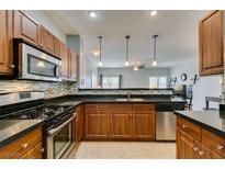 This kitchen boasts stainless steel appliances, wooden cabinetry, backsplash, and a granite countertop at 9362 Straw Hays St # 103, Las Vegas, NV 89178