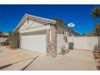 Two car garage with brick accents, concrete driveway and white stucco exterior with a view of the gate at 2004 Canterbury Dr Dr, Las Vegas, NV 89119