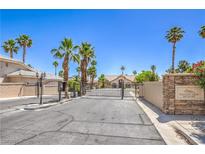 View of the Canyon View Estates entrance, featuring palm trees, mature landscaping and gated access at 2201 Country Cottage Ct, Las Vegas, NV 89117