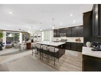 Staged kitchen featuring dark cabinetry, a large island with seating, and seamless flow into the living and dining areas at 234 Polaris Ridge Ave, Henderson, NV 89011