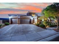 Beautiful home exterior with a three-car garage, desert landscaping, and brick paver driveway at dusk at 7300 Fresh Harvest Ave, Las Vegas, NV 89131