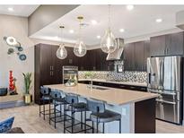 Modern kitchen featuring dark cabinetry, stainless steel appliances, pendant lighting and a spacious island with seating at 4290 Solace St, Las Vegas, NV 89135