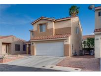 Two-story tan home featuring a white garage door and desert landscaping at 7240 Wandering Star Ct, Las Vegas, NV 89131