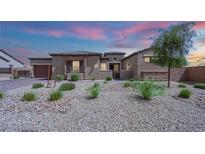 Charming single-story home featuring desert landscaping, stone accents, and a neutral color palette, captured at twilight at 7258 W Le Baron Ave, Las Vegas, NV 89178