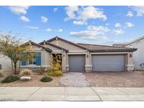 Charming single-story home featuring a tile roof, paver driveway, and a well-manicured front yard at 7616 Quail Dust St, North Las Vegas, NV 89084
