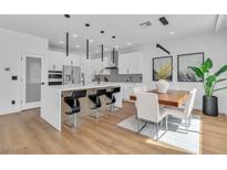 Modern kitchen with white cabinets, stainless steel appliances, island seating, and dining area at 9713 Kampsville Ave, Las Vegas, NV 89148