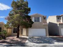 Two-story home featuring a desert landscaped front yard, a large tree, and a two-car garage at 1030 Country Skies Ave, Las Vegas, NV 89123