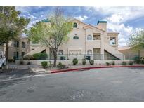 Inviting two-story condo featuring a stucco exterior, private balconies, and lush landscaping under a partly cloudy sky at 2251 Wigwam Pkwy # 716, Henderson, NV 89074