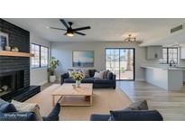 Bright living room with black fireplace, ceiling fan, and sliding door access to the outside at 3484 Nightflower Ln # B, Las Vegas, NV 89121