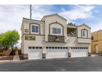Inviting condo building featuring a stucco exterior, multiple garages, and well-kept landscaping at 3920 Smokey Fog Ave # 201, North Las Vegas, NV 89081