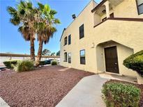 Inviting two-story condo featuring desert landscaping with mature palm trees near the entry at 6137 W Oakey Blvd # A, Las Vegas, NV 89146