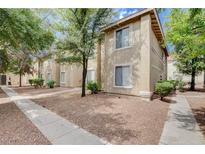 Beige two story home with trees, bushes, and gravel landscape in front at 7200 Pirates Cove Rd # 2084, Las Vegas, NV 89145