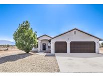Charming single-story home featuring a two-car garage, desert landscaping, and a welcoming front entrance at 861 S Ford Loop, Pahrump, NV 89048