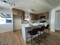 Modern kitchen features an island with seating, stylish lighting, stainless steel appliances, and sleek cabinetry at 1600 E Mcdonald Ave, North Las Vegas, NV 89030