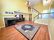Bright living room featuring a fireplace, wood floors, and staircase to the second floor at 1628 Palmae Way, Las Vegas, NV 89128