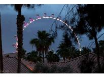 Exterior shot of Ferris wheel with palm trees and roof tile in foreground at night at 270 E Flamingo Rd # 131, Las Vegas, NV 89169