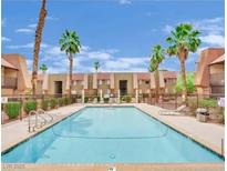 Community pool with palm trees and lounge chairs at 4421 Alexis Dr # 429, Las Vegas, NV 89103