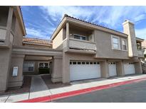Beige townhome exterior with multiple garage doors, balcony, and well-maintained landscaping at 5125 W Reno Ave # 1059, Las Vegas, NV 89118