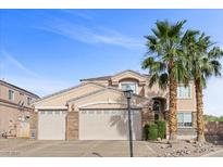 Inviting two-story home with a three-car garage, desert landscaping, and mature palm trees at 644 Wind Cave Ct, Henderson, NV 89012