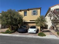 Two story home featuring neutral stucco, brick driveway, desert landscaping, and an attached two car garage at 8675 Scalpay St, Las Vegas, NV 89166
