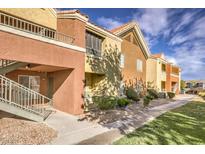 Charming condo building featuring balconies, mature landscaping, and a tiled roof under a partly cloudy sky at 2120 Ramrod Ave # 2216, Henderson, NV 89014