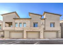 Modern townhome exterior featuring a two-car garage, stone accents, neutral colors, and desert landscaping at 600 N Carriage Hill Dr # 1143, Las Vegas, NV 89138