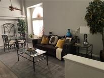 Comfortable living room with a brown sofa, glass coffee table, dining table and a large arched window at 9036 Cotton Rose Way, Las Vegas, NV 89134