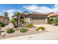 Charming single-story home boasting desert landscaping, including palm trees and cacti, a two car garage, and a welcoming facade at 2120 Desert Woods Dr, Henderson, NV 89012