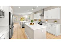 Modern kitchen boasts stainless steel appliances, white cabinetry, an island and wood flooring at 2227 Garden City Ave, Henderson, NV 89052