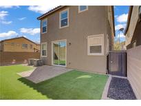 Landscaped backyard featuring artificial turf, a patio, and a sliding glass door for indoor-outdoor living at 9190 Wine Cellar Ave, Las Vegas, NV 89148