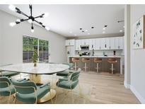 Open floor plan with modern kitchen, island with seating, and dining area with stylish light fixture at 1312 Pacific Terrace Dr, Las Vegas, NV 89128