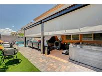 Inviting covered patio features a hot tub, lounge furniture, and shade screens, creating a relaxing outdoor oasis at 1413 Miller Ridge Ave, North Las Vegas, NV 89031